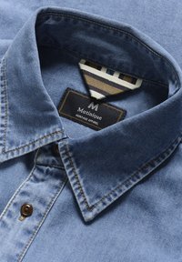 Denim särk, mis on sinise tooni, klassikalise krae, pruuni nupuga ning kontrastset triibulist detailiga sisekrael koos brändi sildiga.