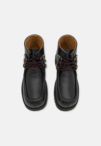 Bottines en cuir noir à finition lisse, avec des lacets rouge et noir, des accents en métal argenté et une doublure intérieure beige.