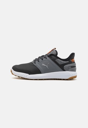 Schwarze und graue Sportschuhe mit einer strukturierten Oberseite, weißer Zwischensohle, Gummiaußensohle und Stoffakzenten am Schaft und Zunge.