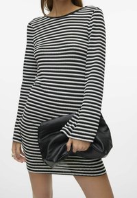 Robe à manches longues à rayures noires et blanches avec une coupe droite, présentant un col rond et des poignets évasés. Une pochette noire texturée est tenue en main.