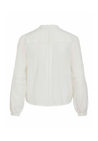 Blouse en lin blanc à manches longues, ornée d'accents en dentelle sur les manches, avec un col rond et une fermeture boutonnée dans le dos.