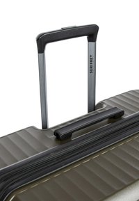 Valise rigide de couleur olive avec surface texturée, poignée télescopique extensible, poignée de transport supérieure et fermeture éclair visible.