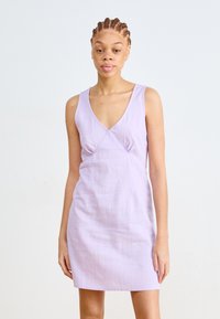 Syre lilac-värinen hihaton mekko, jossa on syvä V-pääntie, teksturoitu kangas ja ryppy yksityiskohtia rinnan alla. Yksinkertainen, muotoiltu siluetti.