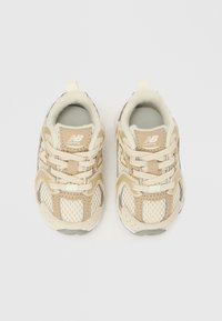 Μπεζ παπούτσια τρεξίματος με ανώτερο μέρος από δίχτυ, συνθετικές επικαλύψεις, υφασμένα πέλματα και κλείσιμο με κορδόνια. Λογότυπο στη γλώσσα και στη φτέρνα. Εσωτερική ελαφριά επένδυση.