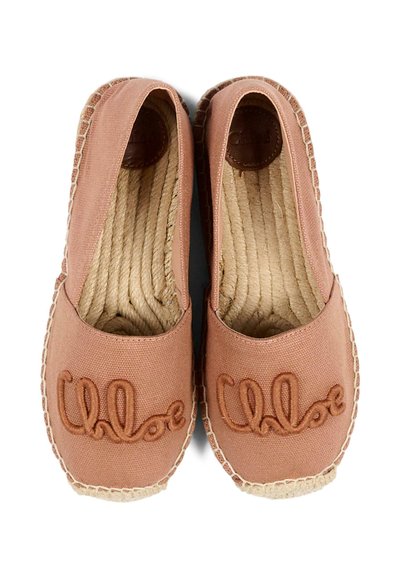 Para jasnoróżowych espadryli z płóciennym wierzchem i podeszwami z liny, z wyszywanym logo "Chloe" na czubkach, widziana z góry.