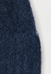 Material tricotat albastru închis, cu o suprafață moale și texturată. Prezintă fibre vizibile și un aspect ușor pufos, potrivit pentru îmbrăcăminte sau accesorii.