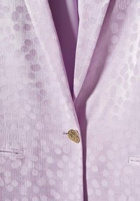 Svetle fialový blazer s texturovanou látkou se spirálovými vzory a zlatým knoflíkem jako akcentem. Obsahuje klopové límce a boční kapsy.