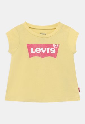Camiseta amarilla de manga corta para niño pequeño con el logo rosa de Levi’s impreso en el pecho, cuello redondo y una pequeña etiqueta roja de Levi’s en la costura lateral.