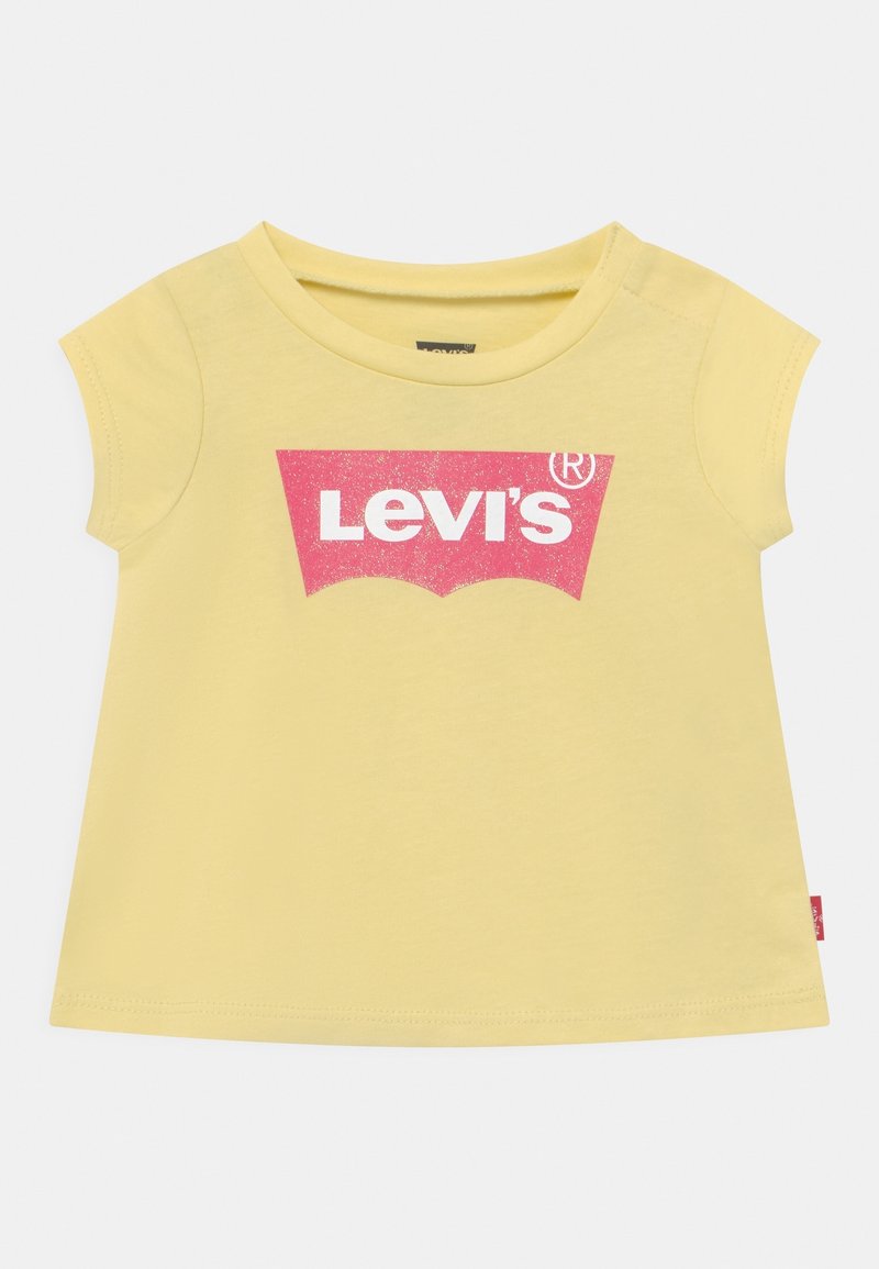 Żółta koszulka dla malucha z krótkim rękawem, z różowym logo Levi’s nadrukowanym na piersi, okrągłym dekoltem oraz małą czerwoną metką Levi’s na bocznym szwie.