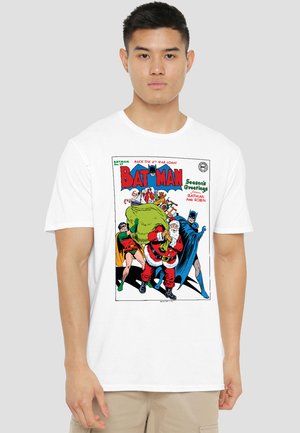 Man wearing white T-shirt with vintage Batman comic cover showing Batman, Robin, and Santa carrying a large green sack of gifts.