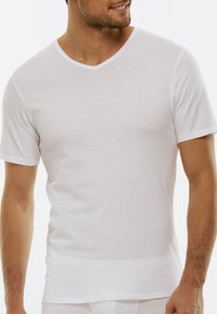 T-shirt bianco in cotone a maniche corte con scollo a V, caratterizzato da una texture liscia e un design aderente senza cuciture visibili.
