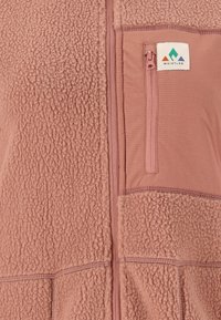 Fleece-Weste in staubigem Pink mit strukturiertem Stoff, horizontalen Nähten und einer Reißverschlusstasche. Mit einem Logo-Patch in der oberen Ecke.