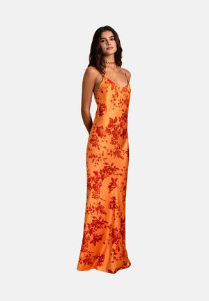 Robe en satin avec des bretelles fines, présentant un fond orange et des motifs floraux rouges. Longueur au sol avec une silhouette ajustée.