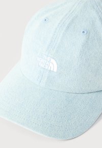 Καπέλο μπέιζμπολ από ανοιχτό γαλάζιο τζιν με λευκό κεντημένο λογότυπο "The North Face" στην μπροστινή πλευρά και ραμμένες οπές εξαερισμού.