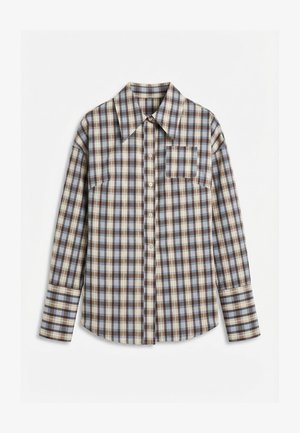 Chemise à manches longues à carreaux boutonnée, avec des motifs bleu, marron et crème, et une poche poitrine avant, posée à plat sur une surface blanche.