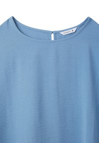 Top blu textured con scollatura rotonda e chiusura a occhio di bue sul retro. Il materiale ha un aspetto morbido e leggero.