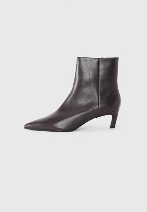 Stivaletto in pelle nera con punta appuntita, tacco medio e texture liscia. Design elegante con dettaglio zip laterale.