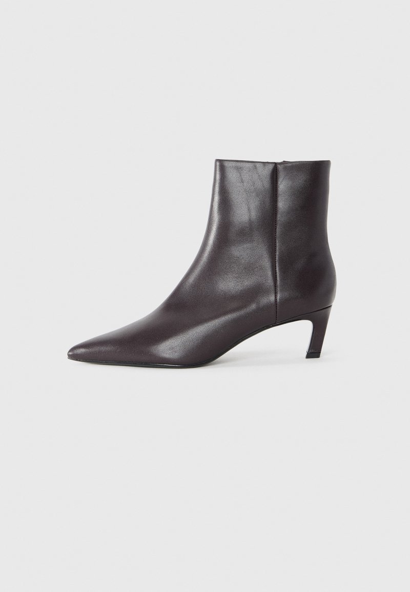 Bottine en cuir noir avec bout pointu, talon moyen et texture lisse. Design élégant avec un détail de fermeture éclair latérale.