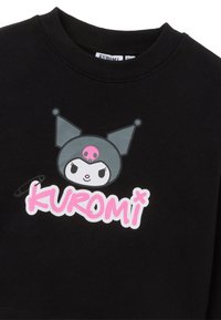 Zwarte sweatshirt met een grafisch ontwerp van een karakter met een roze schedelaccent, vergezeld van de tekst "KUROMI" in het roze.