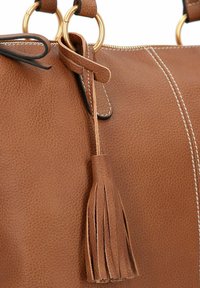 Braune Lederhandtasche mit goldfarbenen Ringbeschlägen, einer strukturierten Oberfläche und einem Lederquasten-Akzent auf einer genähten Naht.