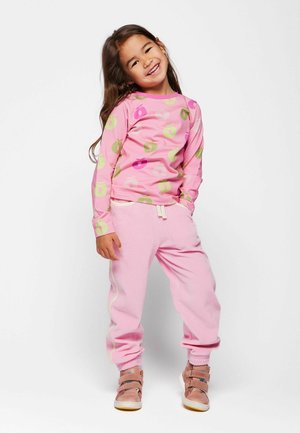 Roza majica z dolgimi rokavi z zelenimi in roza jabolčnimi potiski, kombinirana z usklajenimi roza športnimi hlačami z elastičnimi manšetami in pasom z vrvico.