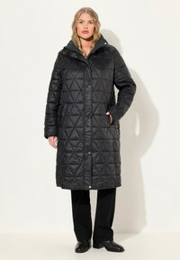 Abrigo largo negro acolchado con capucha verde, con botones a presión, dos bolsillos laterales y una textura sintética suave.