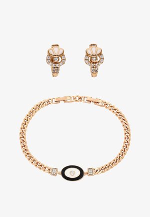 Kultainen rannekoru, jossa on mustavalkoinen soikea keskiosa, ja siihen sopivat kultaiset korvakorut, joissa on valkoista emalia ja kirkkaita kristalleja.