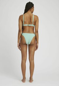Ensemble de bikini à rayures vert menthe, avec des bretelles ajustables et un dos à fermeture. Bas échancré avec une couverture arrière minimale. Texture de tissu lisse.