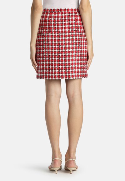 Rød og hvid ternet mininederdel med tekstureret stof, elastisk talje og en lige silhuet, kombineret med lyse højhælede sko.