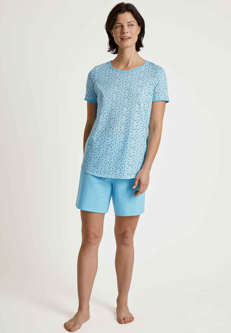 Lichtblauw kort mouwtop met een verspreid patroon en bijpassende blauwe shorts. Katoenen materiaal, relaxed fit, casual ontwerp.