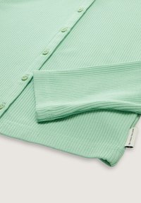 Maglietta a maniche lunghe a coste verde chiaro con chiusura a bottoni, caratterizzata da una texture morbida e un'etichetta di marca sull'orlo.