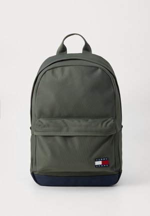 Olive green backpack made of textured fabric, featuring a front pocket, reinforced top handle, and navy blue bottom. Logo displayed prominently.