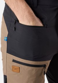 Knälånga byxor med svart och ljusbrun färgblockering, med dragkedjefickor, en texturerad yta och en logopatch.
