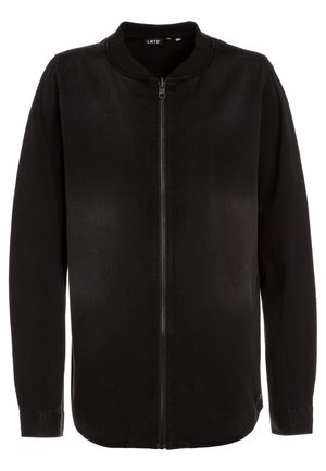 Veste noire à manches longues zippée, col rond et sans poches visibles, présentée sur un fond blanc uni.