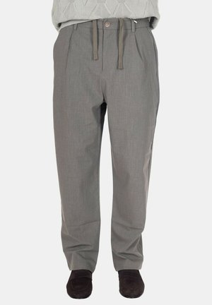 Pantaloni grigi dritti con pieghe, chiusura con bottoni e vita con coulisse, indossati con mocassini scuri e maglione leggero in maglia.