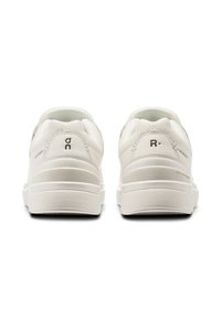 Sneaker bianche con una tomaia in rete testurizzata, suola in gomma liscia e design minimalista. Presenta un logo sul tallone e sui lati.