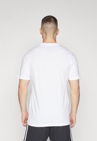 Hvid bomulds t-shirt, korte ærmer, rund hals, afslappet pasform, ingen synlige mønstre eller grafik, set fra bagsiden.