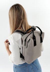 Grauer und schwarzer Rucksack mit Reißverschluss, aus Stoffmaterial, mit zwei Trageoptionen (Träger und obere Griffe) und einem einfachen, strukturierten Design.