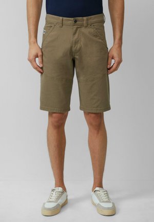 Beige katoenen shorts met een relaxte pasvorm, voorzien van een ritssluiting, voorkoeken en een knielange snit; gecombineerd met lichtkleurige sneakers.