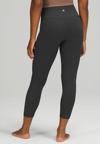 Czarne legginsy high-waisted o gładkiej teksturze; dopasowany krój zwężający się do długości kostki; na tylnym pasie znajduje się małe logo.