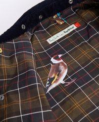 Forro xadrez com tons de verde escuro, castanho e amarelo. Ilustração de pássaro notável e etiqueta "Paul Smith ama Barbour" em creme.