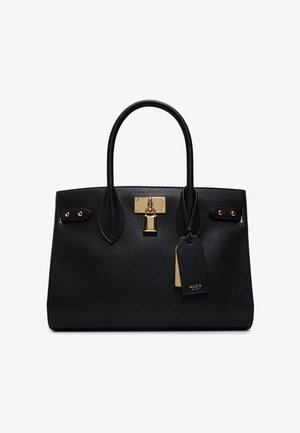 Sac à main en cuir noir texturé avec deux poignées, détail cadenas doré et étiquettes de marque noires et dorées attachées.