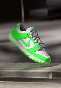 Zöld és fehér Nike Dunk Low cipők, sima bőrből készült felső résszel, perforált orral és texturált elemekkel ellátott gumitalppal.