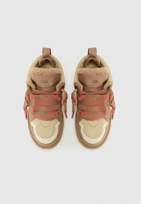 Sneakers marroni e beige con tessuto strutturato, dettagli in pelle, lacci rossi e colletto foderato in pelliccia. Marchio UGG sul tallone.