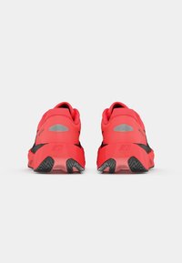 Des chaussures de course rouges avec des accents noirs, en matériau texturé, un col rembourré et une semelle en caoutchouc avec un motif de semelle pour une meilleure adhérence.