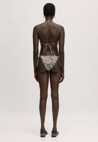 Bikini met halternek en strikdetail aan de achterkant, met een zebra-print in beige en bruin op de onderkant. Soepele, lichte stof.