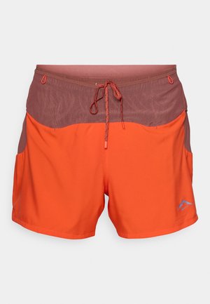Shorts de sport orange avec une ceinture en mesh rouge foncé, cordon ajustable, poches latérales et un petit logo bleu sur la jambe avant gauche.
