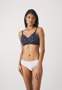 Sutiã azul-marinho com padrão florido, tecido suave, design em V, alças ajustáveis. Faca de cintura baixa branca com textura lisa e detalhes mínimos.