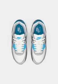 Nike Air sneakers feature a white mesh upper with gray and blue accents, flat white laces, and a black rubber sole.