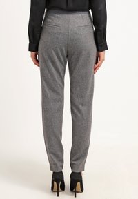 Pantaloni gray su misura con una finitura in tessuto morbido. Presentano una vita piatta, due tasche posteriori e gambe affusolate. Abbinati a tacchi neri.